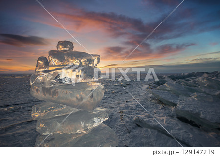 Sunset reflected in a large block of ice hummock on the frozen lake background. Sunset reflected in a large block of ice hummock on the frozen lake background. 129147219