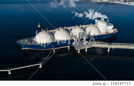 Aerial of Liquified Natural Gas LNG carrier moored to a small gas terminal at night. Fuel crisis. Sanctions. 129147717