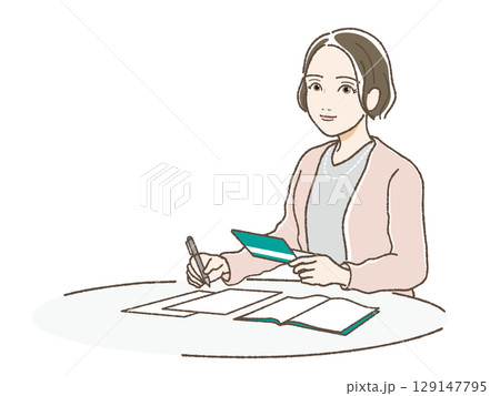 通帳をみながら書類に記入する女性 129147795
