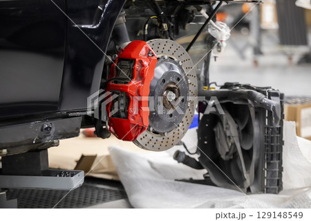 Front disc brake system on race car in process of damaged tyre replacement. The rim is removed showing the front rotor and caliper. Front disc brake system on race car in process of damaged tyre replacement. The rim is removed showing the front rotor and caliper. 129148549