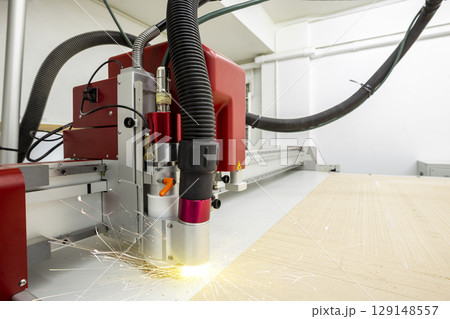 CNC laser cutting metal sheet with bright sparkle in factory. 129148557