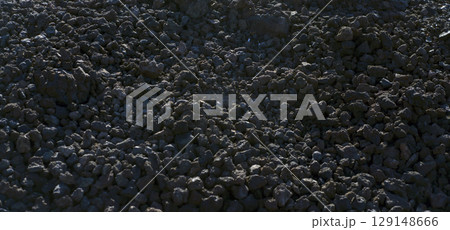 Black volcanic desert land with basalt lava formations and stones, a dark soil of the volcano. 129148666