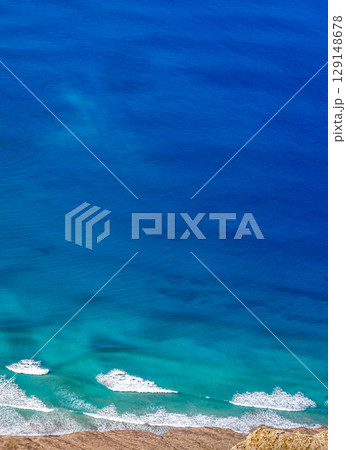Blue ocean with waves and a sandy beach, top view. 129148678