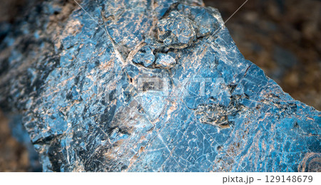 A blue natural stone with lots of details closeup, a piece of volcanic origin stone. 129148679
