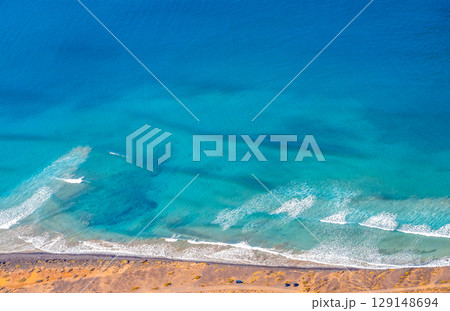 Blue ocean with waves and a sandy beach, top view. 129148694