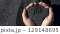 A person is holding a black volcanic sand in his or her hands, closeup view. 129148695