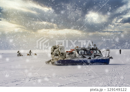 People travel, dogsledding on the ice of frozen Baikal Lake in a safe and comfortable Hivus hovercraft. 129149122