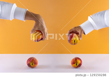 Two male hands with a peach over the table on a colored background 129150286