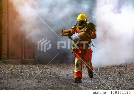 Firefighter rescue, Fireman walking out from burning building and hold save a child in his arms from fire incident. Firefighter rescue, Fireman walking out from burning building and hold save a child in his arms from fire incident. 129151150