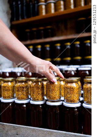 Female hand picking jar of bee pollen in farmer market display Female hand picking jar of bee pollen in farmer market display 129151213