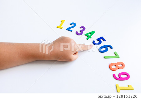 Child hand pointing at sequence of colorful numbers on white background Child hand pointing at sequence of colorful numbers on white background 129151220