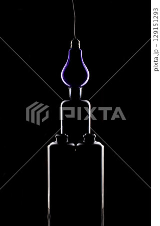 Still life with glass objects and light bulb on a black background Still life with glass objects and light bulb on a black background 129151293