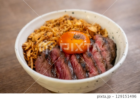 A bowl of Medium rare striploin steak, fried garlic with pickled egg yolk on top. 129151496