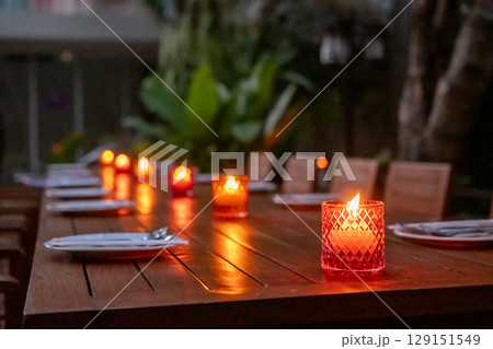 Candle in colorful glass, on the table in the outdoor restaurant 129151549