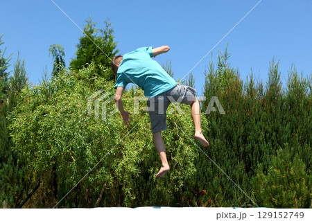 A Boy Joyfully Jumping in the Air on a Beautiful Summer Day Enjoying Life and Freedom 129152749