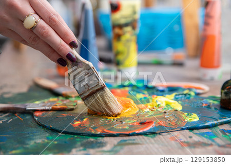 A vibrant array of colorful painting tools and a palette are displayed in a creative art studio A vibrant array of colorful painting tools and a palette are displayed in a creative art studio 129153850
