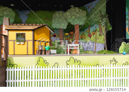 Easter decoration for children on stage with a yellow house and a large easter egg. 129155714