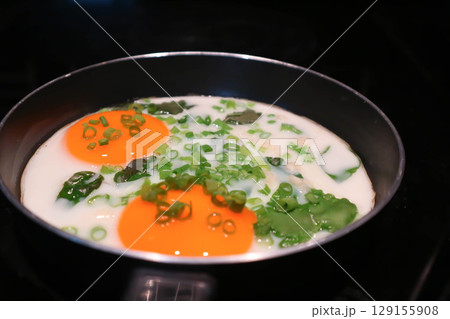 fried egg or sunny side up egg with vegetable topping in a pan 129155908