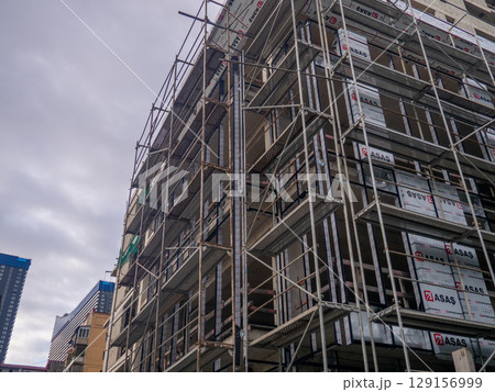 Construction of a concrete house. Modern buildings. Scaffolding. Industrial background. 129156999
