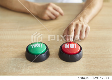 Man chooses between YES and NO buttons on table, makes decision and pushes NO button 129157054