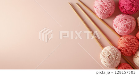 Delicate banner with space for text for knitting related topics and yarn shops, pink balls of yarn and wooden knitting needles on light background 129157503