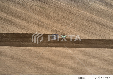 plowing farm after harvesting with vehicle 129157767