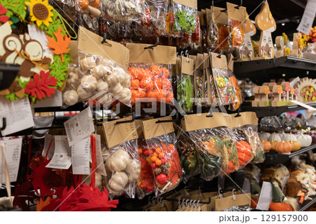 Various autumn decorative items, including pumpkins, leaves, and berries, packaged for sale on a retail shelf, symbolizing seasonal home decor 129157900