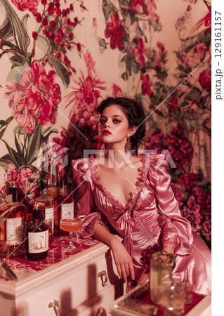 A woman is sitting in front of a table with several bottles and glasses 129161157