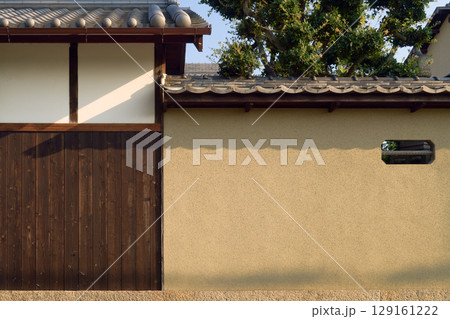 伝統的な日本建築の背景用素材。土壁と焼杉と漆喰の壁と瓦屋根 129161222