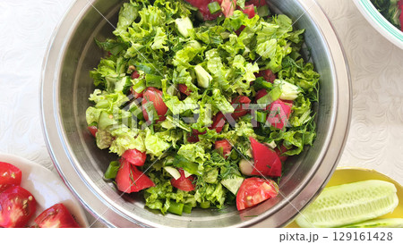A bowl of fresh green salad with lettuce, dill, tomatoes and cucumbers. Spring summer salad of fresh vegetables. Diet healthy food.  129161428