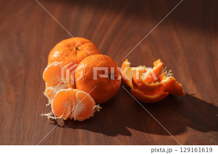Peeled tangerines on a walnut wood table 129161619