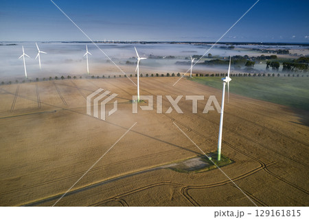 onshore wind turbine standing in fog in the morning sun 129161815