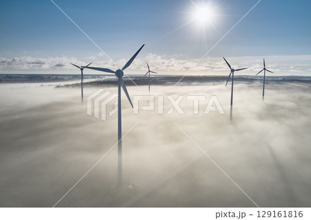 onshore wind turbine standing in fog in the morning sun 129161816