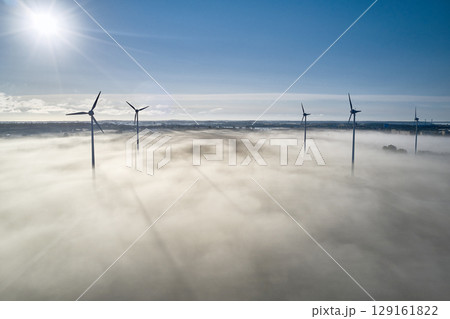 onshore wind turbine standing in fog in the morning sun onshore wind turbine standing in fog in the morning sun 129161822