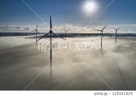 onshore wind turbine standing in fog in the morning sun 129161824