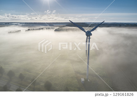 onshore wind turbine standing in fog in the morning sun onshore wind turbine standing in fog in the morning sun 129161826