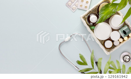 Set of medications with a stethoscope on a blue background with green leaves and copy space. Concept of medicine, healthcare and medication treatment. First aid kit, medicine box. Flat lay 129161942