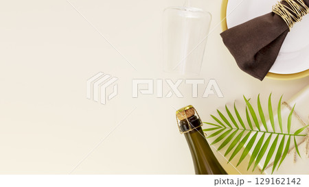Holiday table setting. Present with palm leaf, bottle of champagne and glass on a beige background with copy space. Rosh hashanah, Jewish New Year holiday. Flat lay 129162142