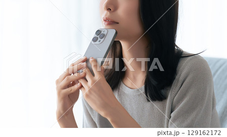 スマートフォンを持って考えごとをする女性 129162172
