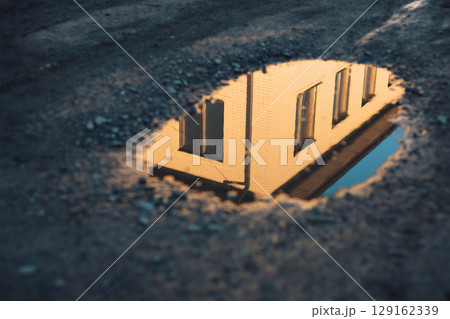The reflection of a building in a puddle on a dirt road The reflection of a building in a puddle on a dirt road 129162339