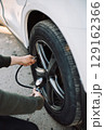Person uses a tire pressure gauge to check the air in a car tire for safety 129162366
