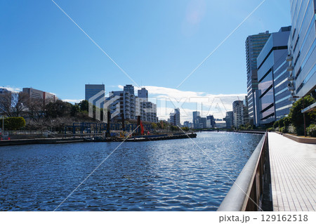 青い空の下、高層ビル群と広い運河が広がる東京ベイエリアの都市景観 青い空の下、高層ビル群と広い運河が広がる東京ベイエリアの都市景観 129162518