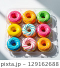 Donuts with colorful icing in a plastic tray. 129162688