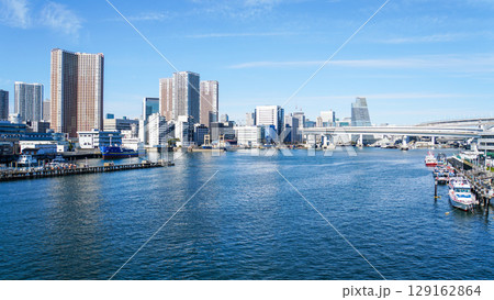 晴れた東京湾に浮かぶボートと、現代的な高層ビルが並ぶ東京の都市風景 晴れた東京湾に浮かぶボートと、現代的な高層ビルが並ぶ東京の都市風景 129162864