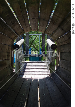 公園の遊び場の木製遊具のトンネルの中 129163231