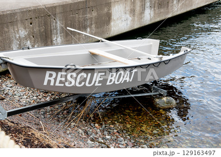 Rescue boat stationed on rocky shoreline near harbor 129163497