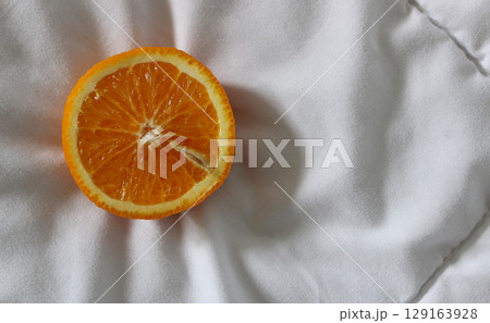Cut in half fresh orange fruit on a quilted blanket at a side of image concept for logo or titles 129163928