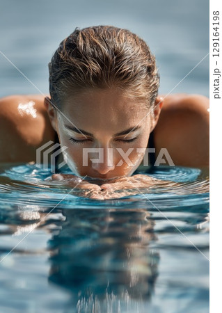 Diver preparing for springboard dive, focused expression, water surface reflecting sunlight 129164198