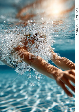 Diver gracefully plunges into water, creating splashes and ripples in a serene aquatic environment 129164199