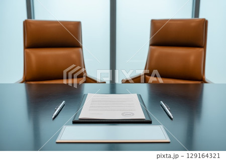 Conference room with empty leather chairs and document on a polished wooden table 129164321